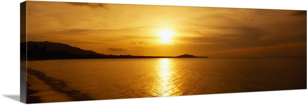 A beautiful sunset is photographed in panoramic view over the ocean water in Thailand.