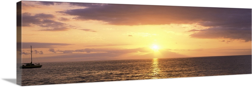 Panoramic photograph on a large wall hanging of a single boat floating on rippling waters at sunset, in Maui, Hawaii.