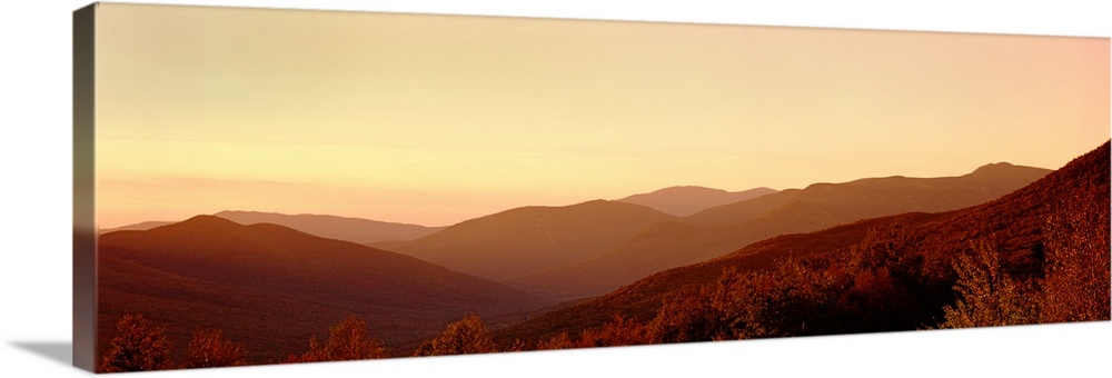Large panoramic image of rolling mountains in the foggy sunset.