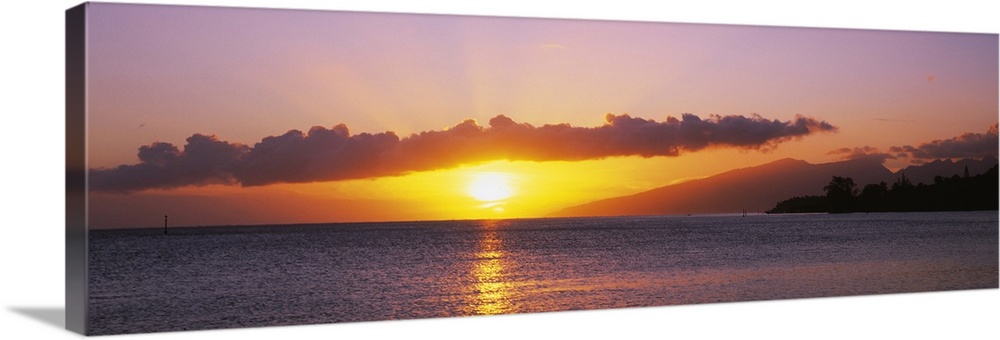 Panoramic photograph of sun and clouds over ocean at dusk.