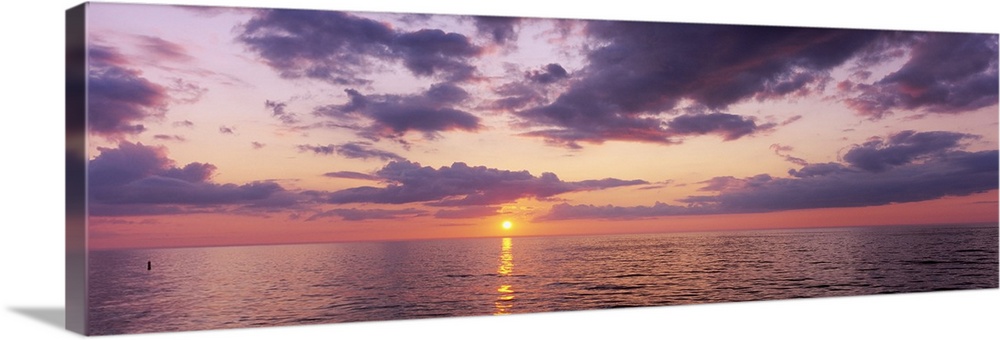 Panoramic photograph taken of a sun setting over the Gulf of Mexico with warm colors throughout the sky.