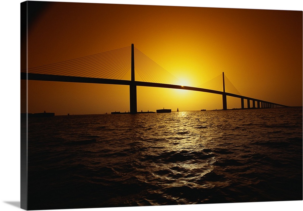 Setting sun framed by the two towers of the Sunshine Skyway bridge, a concrete cable-stayed structure in Florida.