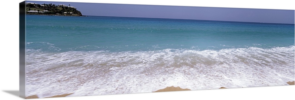 Panoramic image of waves washing ashore from a crystal clear ocean.
