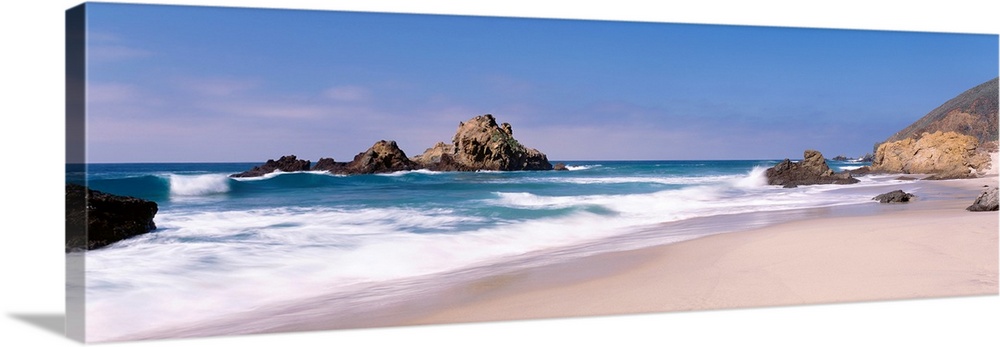 Panoramic photographs displays the Pacific Ocean crashing into the sandy shores of this beach.  Located near the shore are...