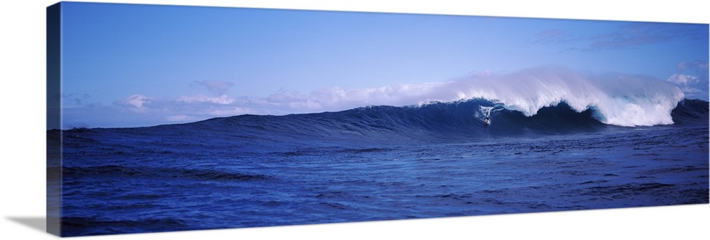 Panoramic image of a surfer riding a large breaking wave.