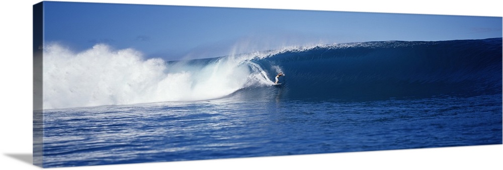 A brave surfer cuts across a plunging wave as it breaks behind his board, almost enclosing him in the tube.