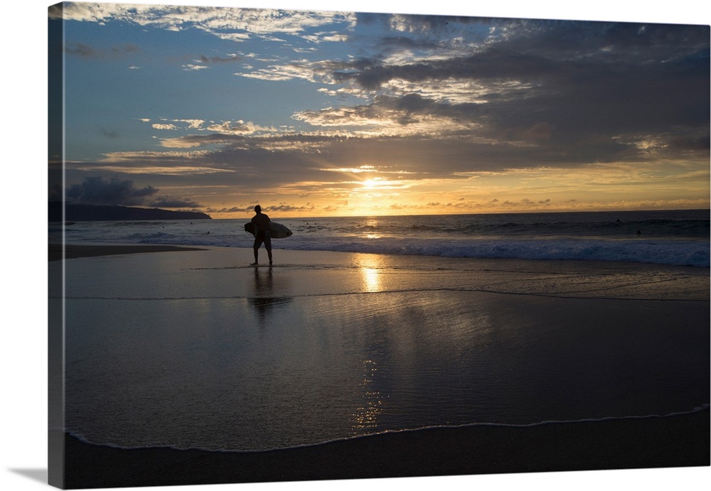 Surfer walking on the beach at sunset, Hawaii, USA