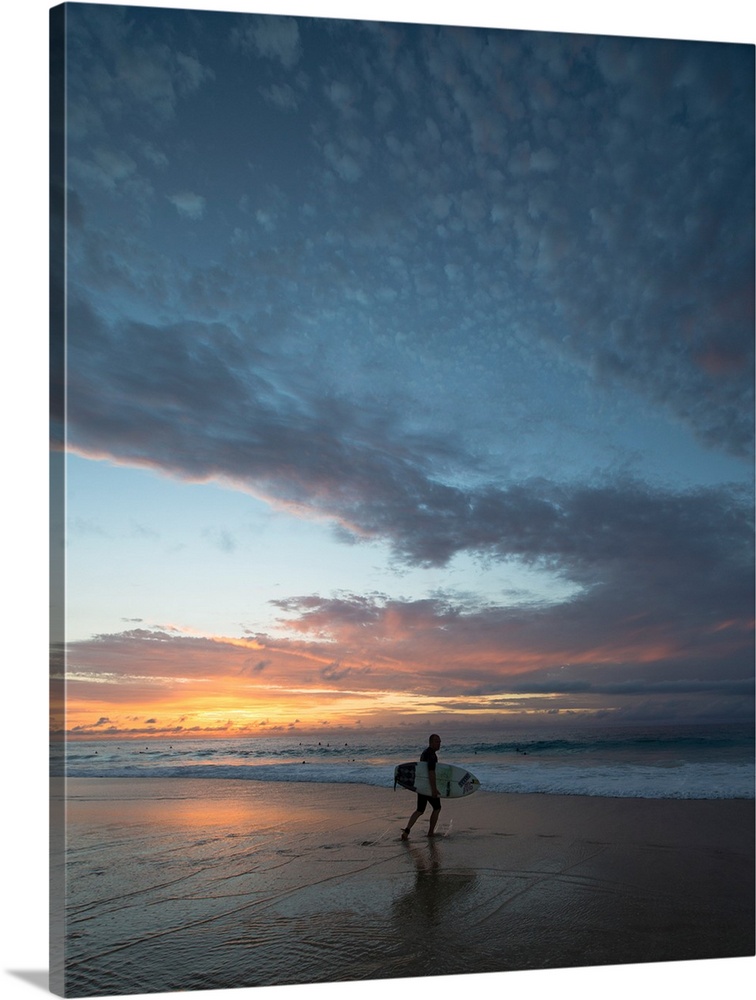 Surfer walking on the beach at sunset, Hawaii, USA