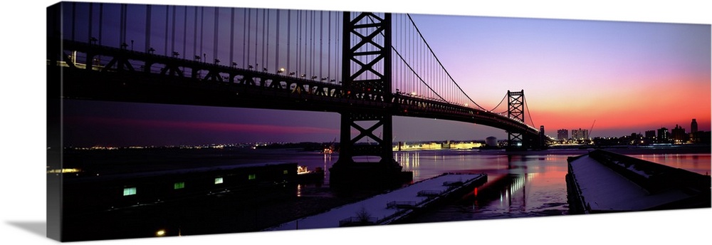 Long horizontal photo print of a big bridge in Philadelphia reaching across a river at sunset.