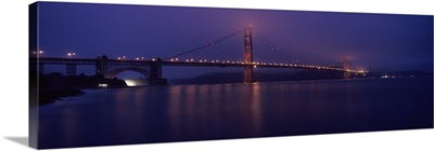 Suspension bridge lit up at dawn viewed from fishing pier Golden Gate Bridge San Francisco Bay San Francisco California