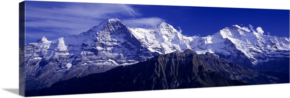 Giant, landscape photograph of snow covered Swiss mountains against a deep blue sky in Berner, Oberland, Switzerland.
