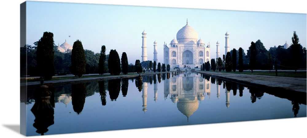 Landscape photograph on a large wall hanging of 17th-century Taj Mahal reflecting in the water, surrounded by trees, in Ag...