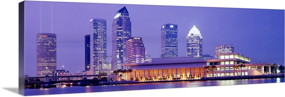 The Tampa skyline is photographed in panoramic view during the night with the buildings all illuminated.