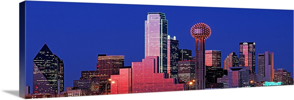 This wall art is a panoramic photograph of the city skyline glowing and glimmering in the night sky.