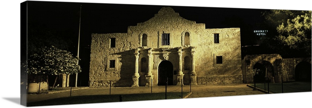 Large, panoramic photograph of New Mexico's famous Alamo, shone in the light as it is surrounded by the blackness of night...