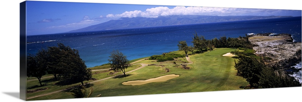 This panoramic photograph is a golf landscape overlooking the ocean from a tropical island.