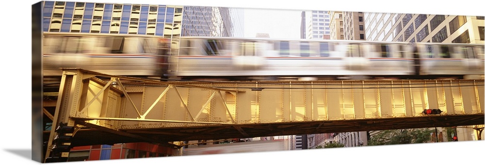 Pamoramic style photo of a commuter train in Chicago flying by on an elevated bridge in downtown.