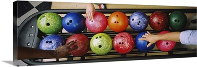 Three peoples hands choosing bowling balls