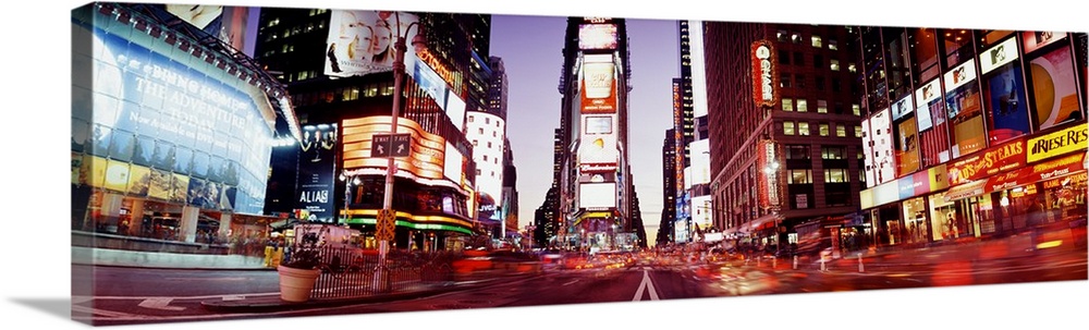 Part of Times Square is photographed in panoramic view while it's illuminated under the dusk sky.