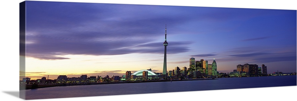 This panoramic view is the city skyline at twilight taken from over the water.