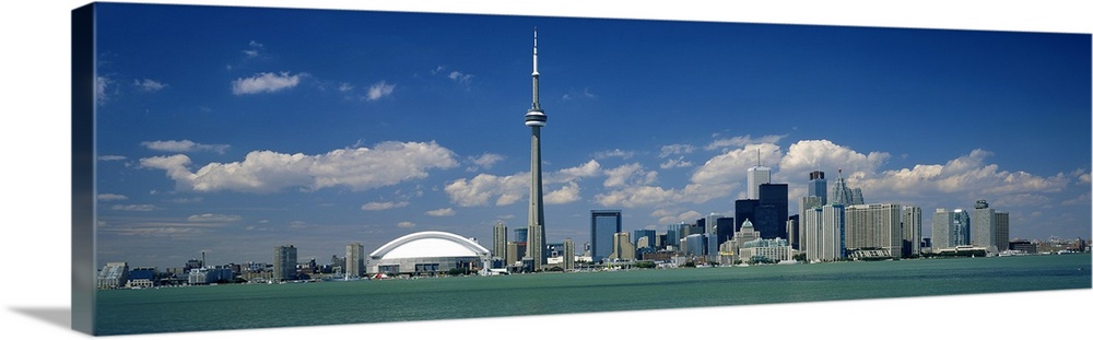 Wide angle photograph on a large canvas of the Ontario skyline, including the CN Tower, in front of a bright blue sky.