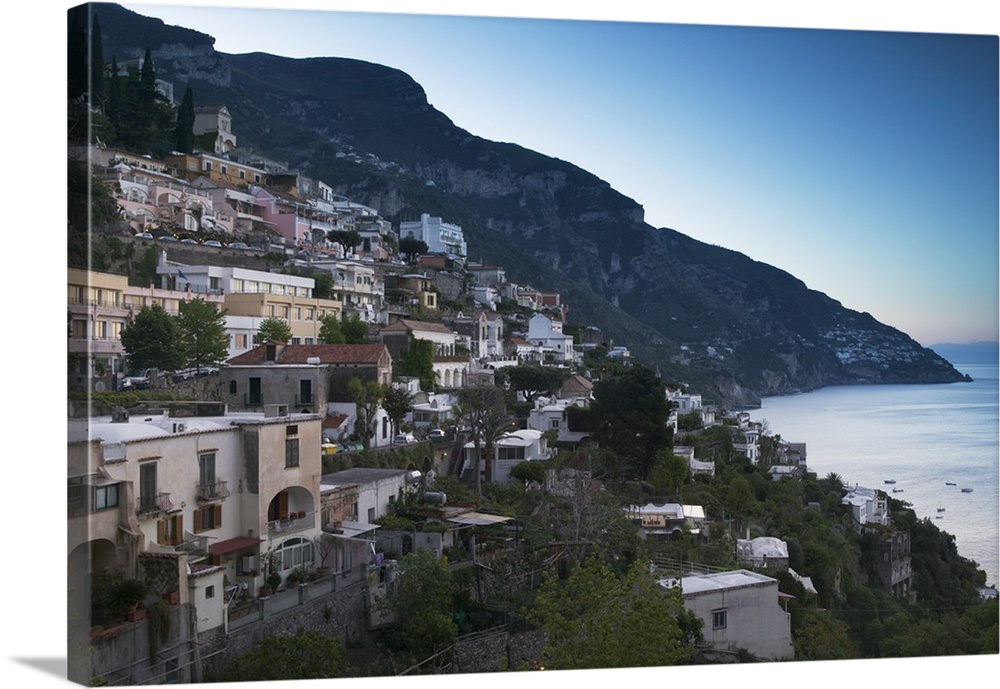 Oversized artwork that is a picture of a town on a coast in Italy. A large hill is seen in the distance with water to the ...