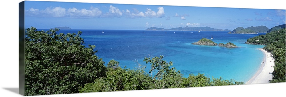 Panoramic photo of a tropical sandy beach, with lush jungle vegetation around the edge, sailboats dotting the ocean.