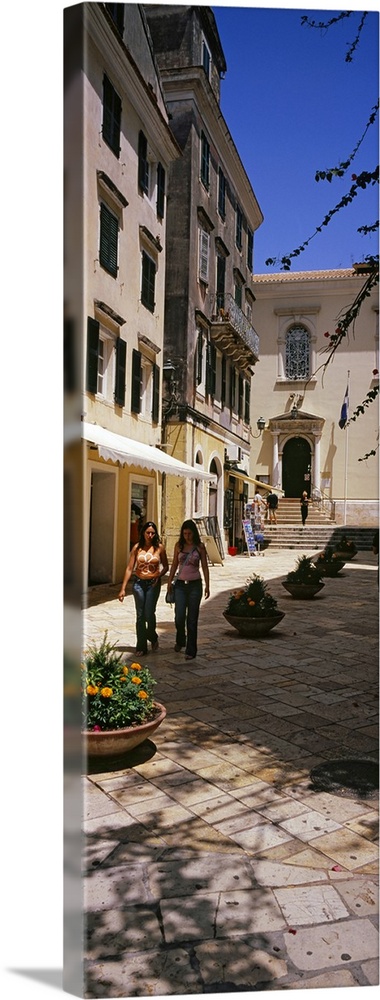Two women walking in front of a courtyard in Corfu Old Town, Corfu, Greece