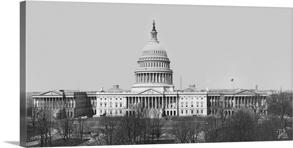 Big, horizontal vintage photograph of the Capitol Building in Washington DC, beneath a clear sky and surrounded by bare tr...