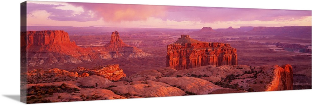 Wide angle, aerial photograph of the rocky terrain at Canyonlands National Park in Utah, beneath a pastel sky.