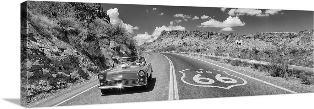 Panoramic photo of a retro car driving down a road on Route 66 in Arizona.