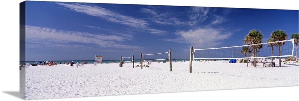 Row of empty volleyball courts on the white sand beach on a clear day.