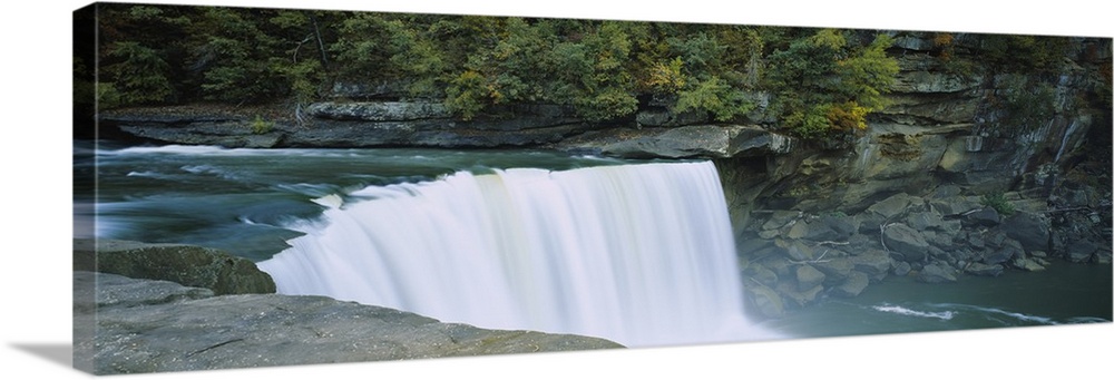 Wall docor of a wide waterfall off of a rocky cliff flowing into a pool of water.