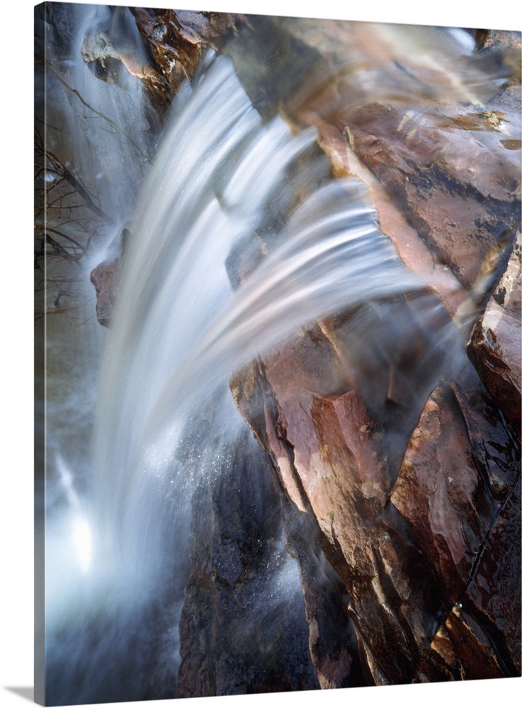 This photograph is taken from the top of a waterfall as it rushes down over a rocky cliff.