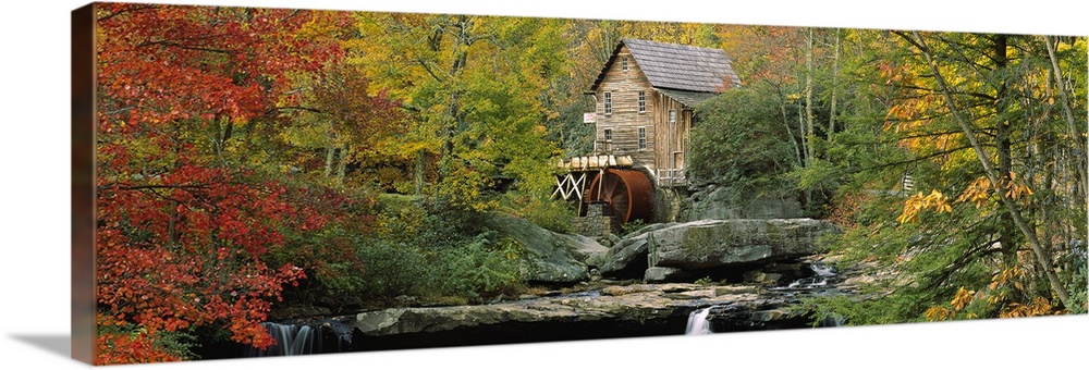 Panoramic photograph of mill in forest surrounded by fall foliage.