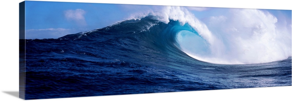 A panoramic photograph capturing a plunging wave in motion as it prepares to break on the surface of the sea.