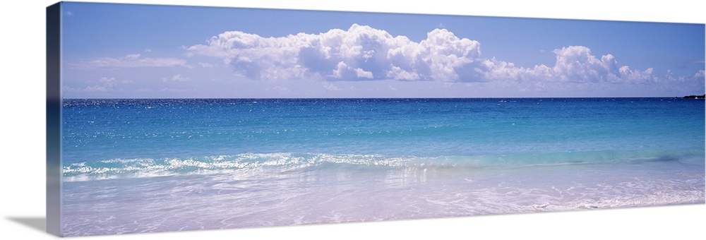 Giant, landscape photograph of a shoreline in Vieques, Puerto Rico.  Small waves of clear blue water rush into the shore.