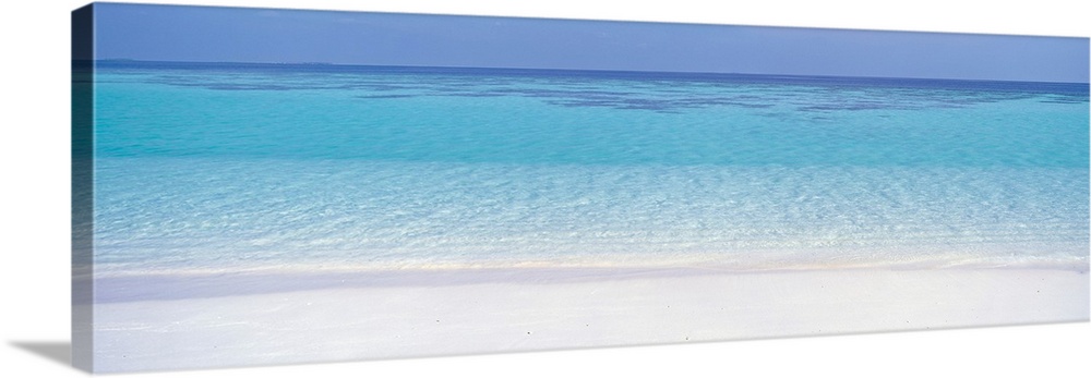 This panoramic photograph shows clear tropical water creating ripples against the shore.
