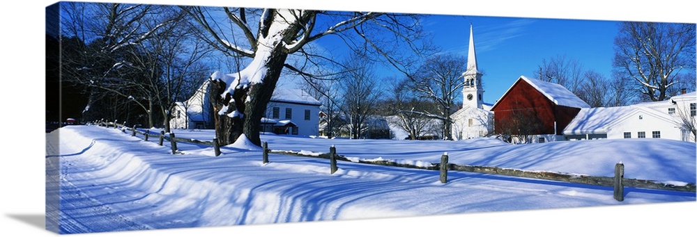 Large, horizontal photograph of a snow covered landscape next to the road in Peacham, Vermont.  Several buildings can be s...