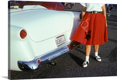 Woman In Red Poodle Skirt And Saddle Shoes Next To White 1950s Car