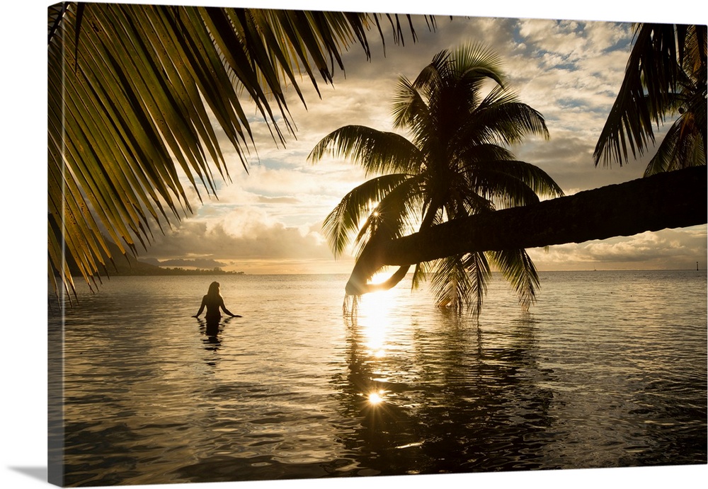 Woman standing in the Pacific Ocean at sunset, Moorea, Tahiti, French Polynesia