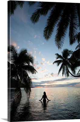 Woman standing in the Pacific Ocean at sunset, Moorea, Tahiti, French Polynesia