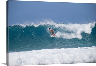 Woman surfing down a wave on beach, Hawaii