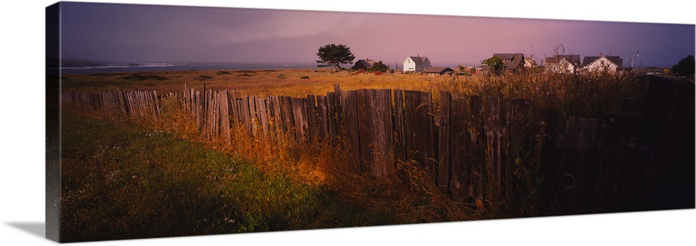 Wooden fence in a field with houses in the background, Mendocino, California