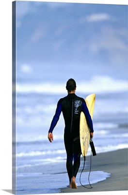 Male surfer walking on the beach in San Diego, CA