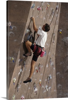 Man wall climbing indoors with equipment