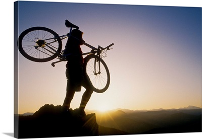 Silhouette of mountain biker at the summit during sunrise