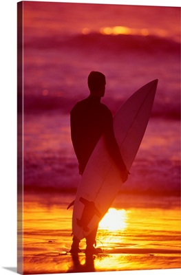 Surfer watching ocean sunset