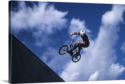 Teenage boy flies over the vert on a BMX bike