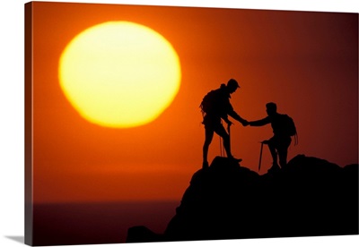 Two climbers reach the summit at sunrise